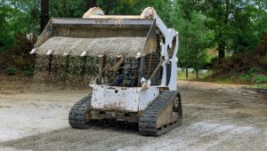 In construction work, bobcat mini loader is moving a bucket full of crushed stone gravel